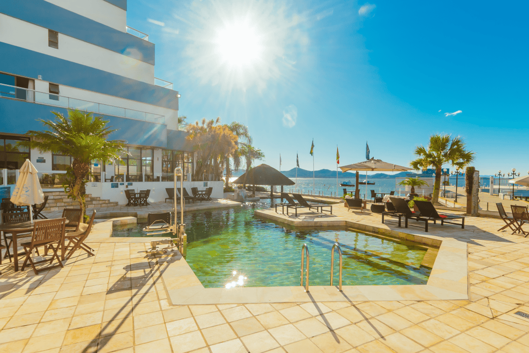 Piscina externa aquecida do Hotel VillaReal em São Francisco do Sul, com espreguiçadeiras, área de lazer ao ar livre e vista para a Baía da Babitonga.